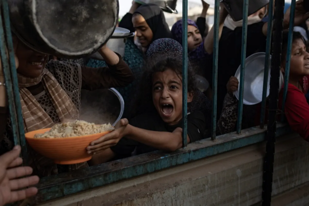 Displaced Palestinians collect donated food in Khan Yunis camp