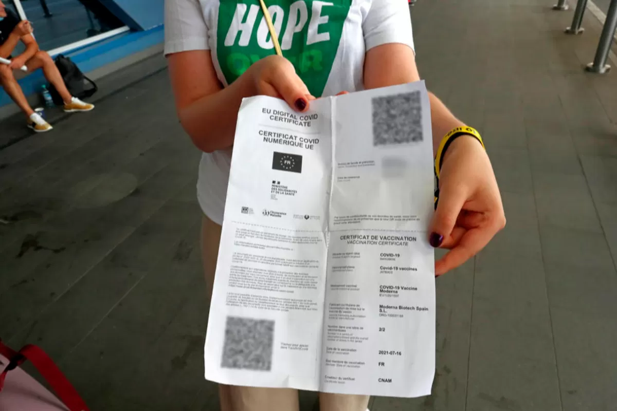O româncă, rezidentă în Franța, își arată Certificatul de sănătate tipărit, în fața terminalului de plecări al Aeroportului Internațional Henri-Coanda, în Otopeni, România, 13 august 2021.
