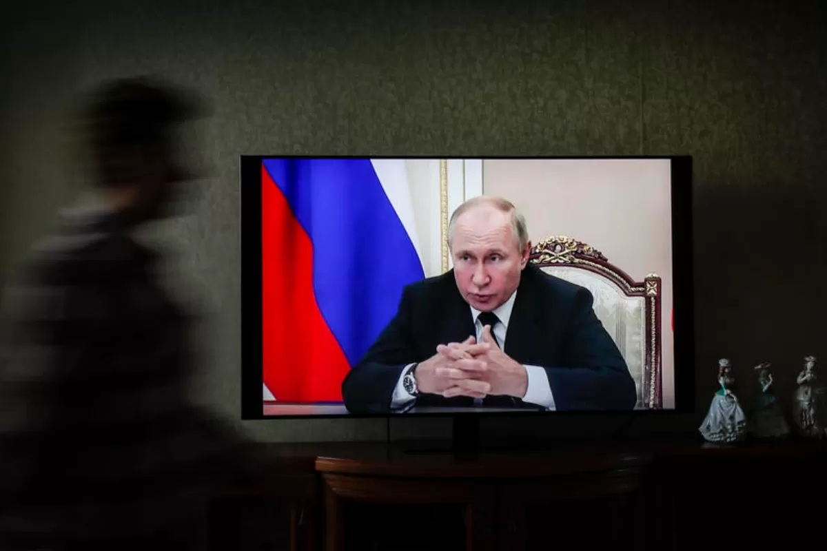 O femeie trece prin fața unui televizor care îl arată pe președintele rus Vladimir Putin la Moscova, Rusia, 14 septembrie 2021.