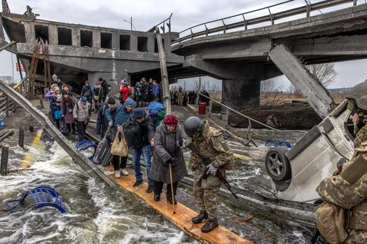 Oamenii traversează podul distrus în timp ce fug din orașul Irpin din prima linie, regiunea Kiev, Ucraina, 7 martie 2022.
