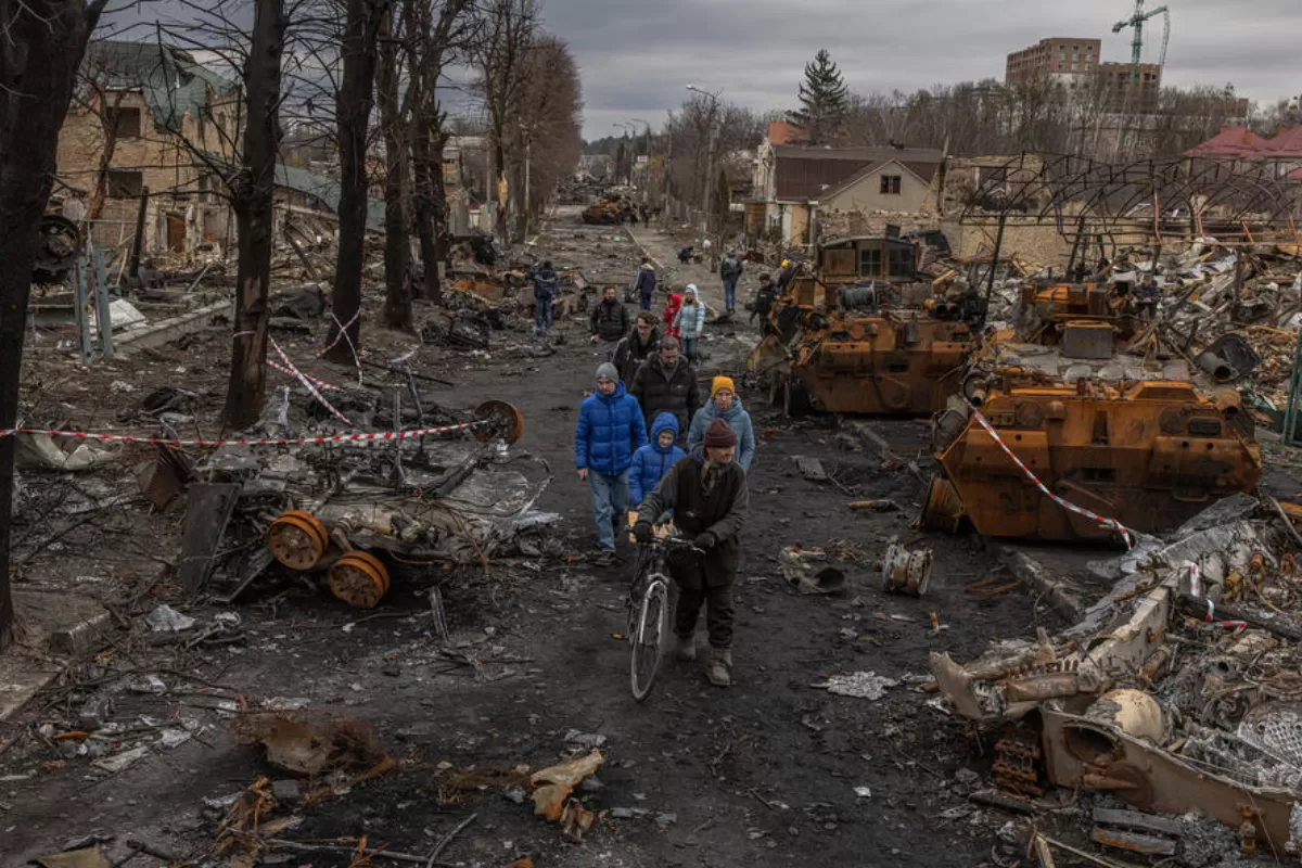 Locuitori trec pe lângă vehicule militare rusești distruse pe stradă, în Bucea, orașul care a fost recapturat de armata ucraineană, la nord-vest de Kiev, Ucraina, 6 aprilie 2022.