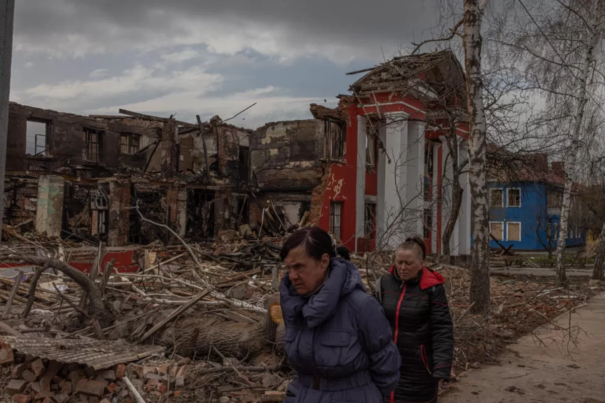Oameni trec pe lângă liceul al tehnologiilor alimentare și comerțului, distrus după un bombardament recent al artileriei ruse, din Harkov, nord-estul Ucrainei, 14 aprilie 2022.