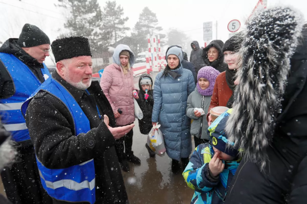 Un preot ortodox voluntar român vorbește cu ucrainenii care au trecut prin punctul de trecere a frontierei Siret, nordul României, 08 martie 2022.