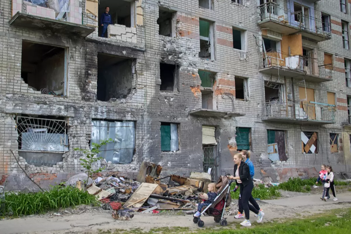 Localnicii trec pe lângă o clădire care a fost avariată în timpul bombardamentelor de la periferia orașului Harkov, Ucraina, 25 mai 2022.