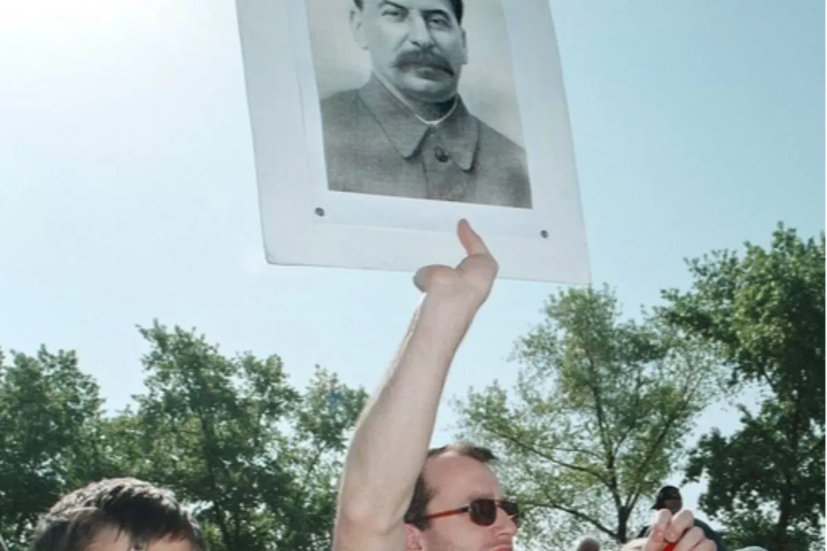 Un moldovean flutură un portret al fostului lider sovietic Iosif Stalin în timp ce ține, împreună cu un băiat, un steag roșu pe care scrie „Uniunea Sovietică este țara noastră” în timpul unui marș de comemorare dedicat celei de-a 58-a aniversări de la sfârșitul celui de-al Doilea Război Mondial în , Chișinău, Moldova, vineri 09 mai 2003.