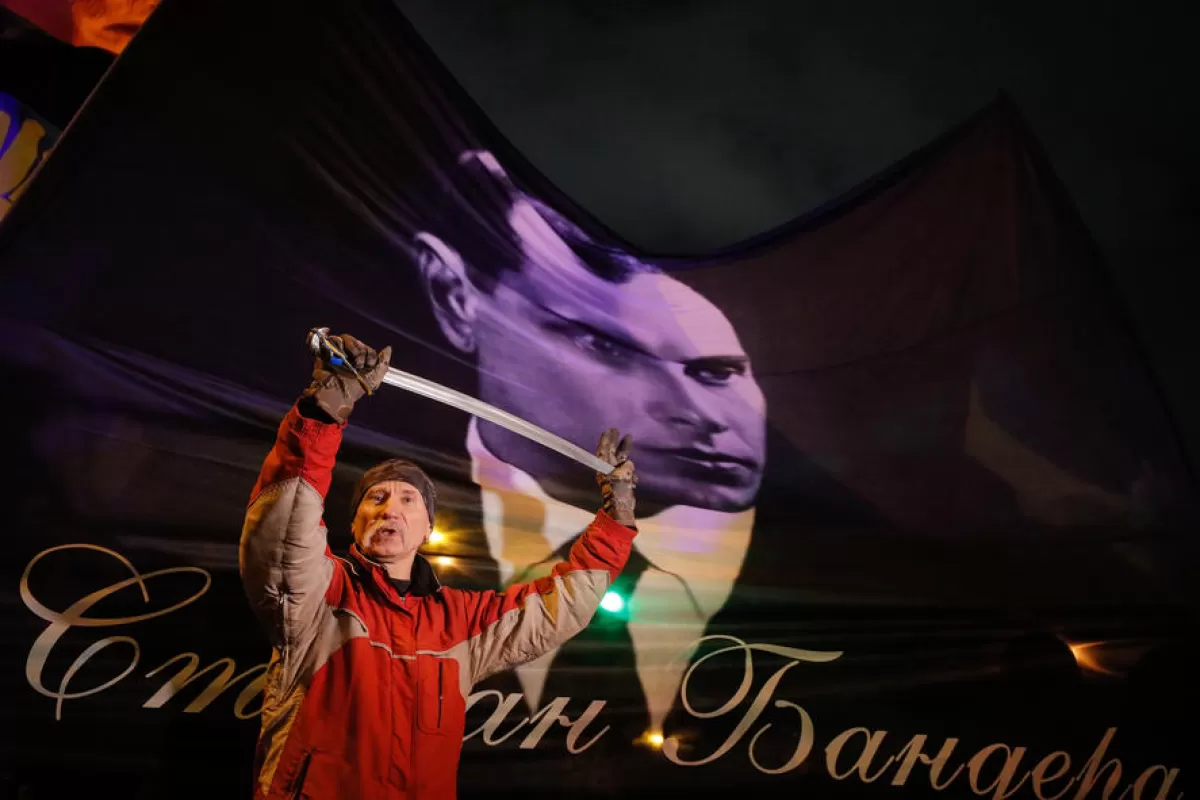 Un activist ține o sabie în fața unui steag cu portretul lui Bandera în timpul unui miting al diferitelor partide naționaliste pentru a marca cea de-a 113-a naștere a lui Stepan Bandera, la Kiev, Ucraina, 1 ianuarie 2022.