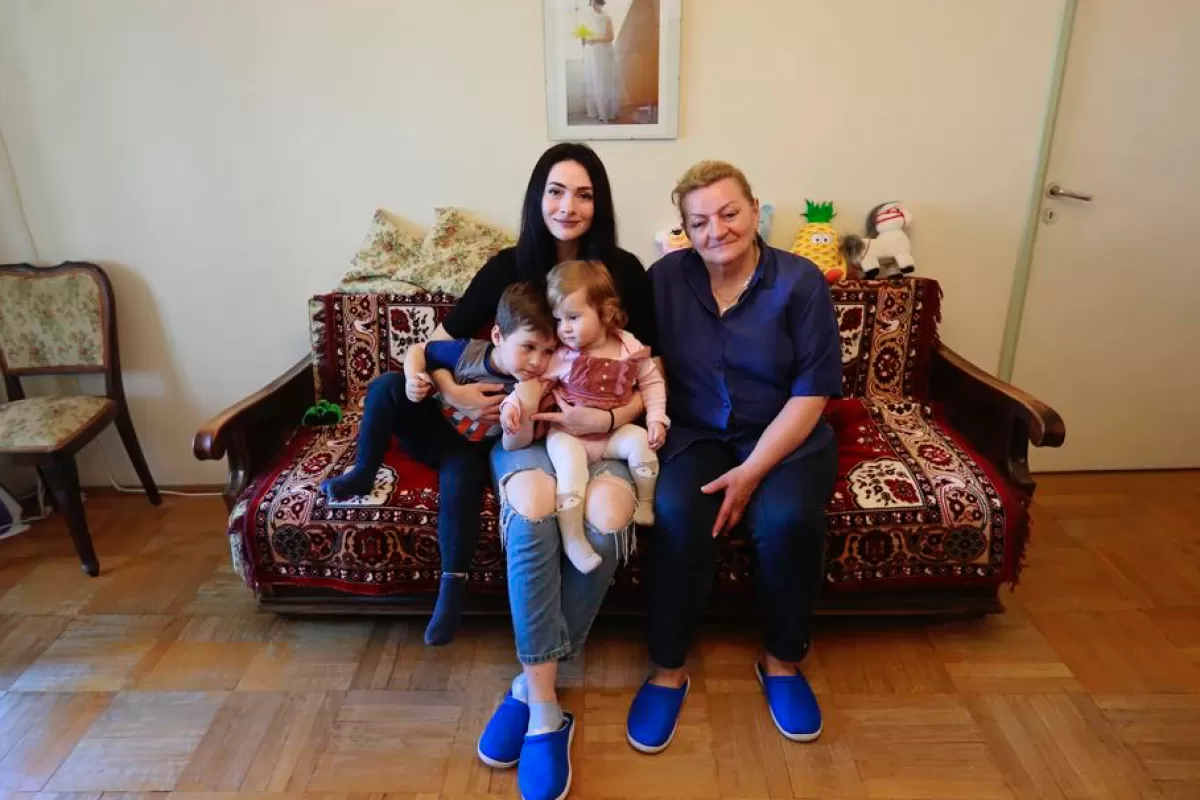 Украинская беженка Ольга позирует для семейного фото на диване в гостиной квартиры, где она находится, Бухарест, Румыния, 14 апреля 2022 года.