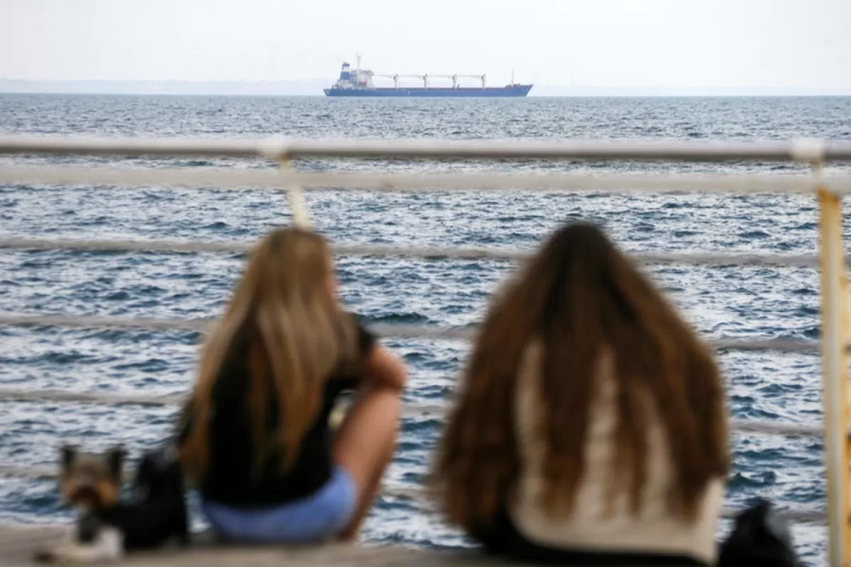 People watch Sierra Leone-flagged cargo ship 'Razoni' leave the port of Odesa, Ukraine, 01 August 2022.