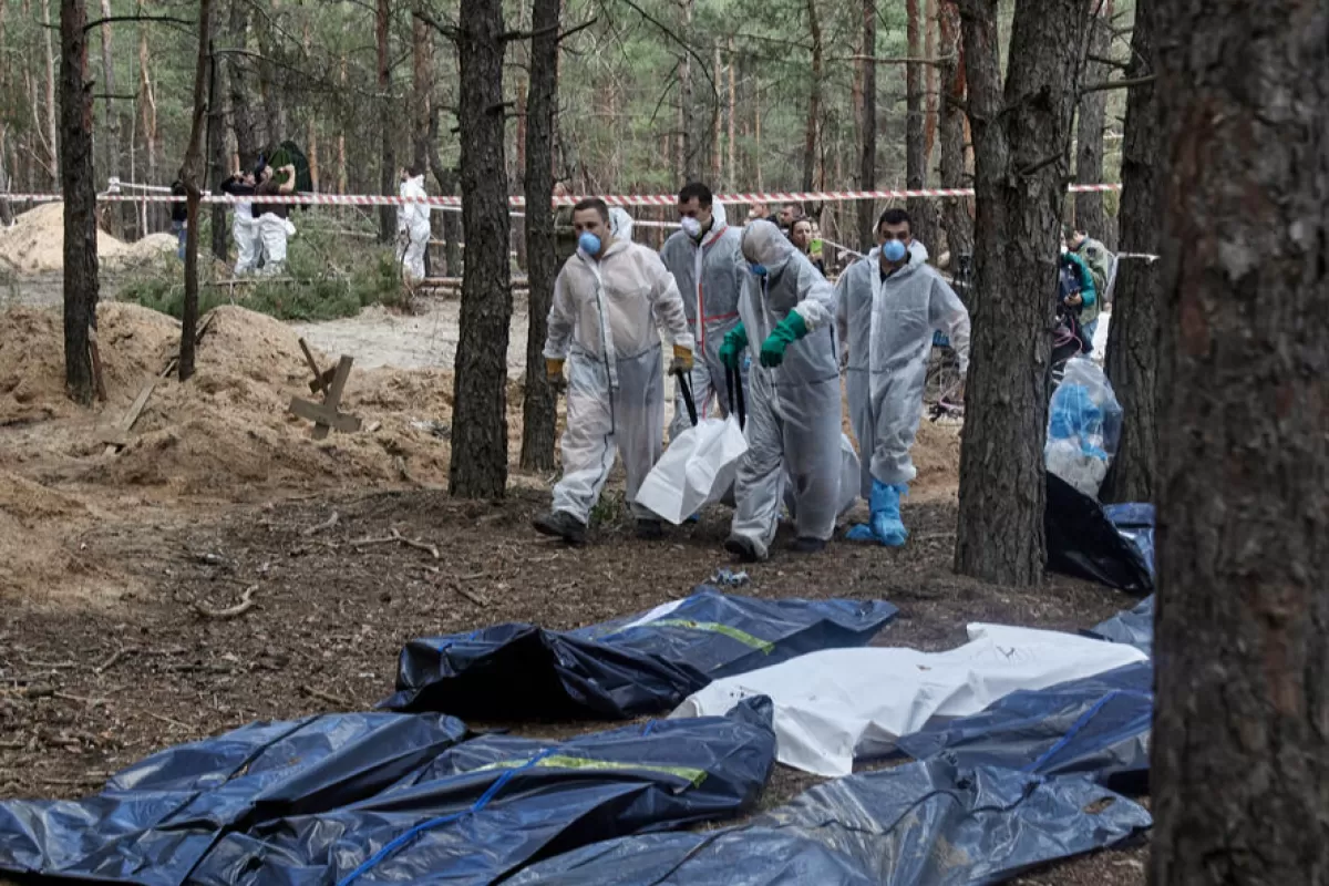 Ukrainian workers carry bodies that were unearthed from graves in Izyum, Kharkiv region, northeastern Ukraine, 19 September 2022.