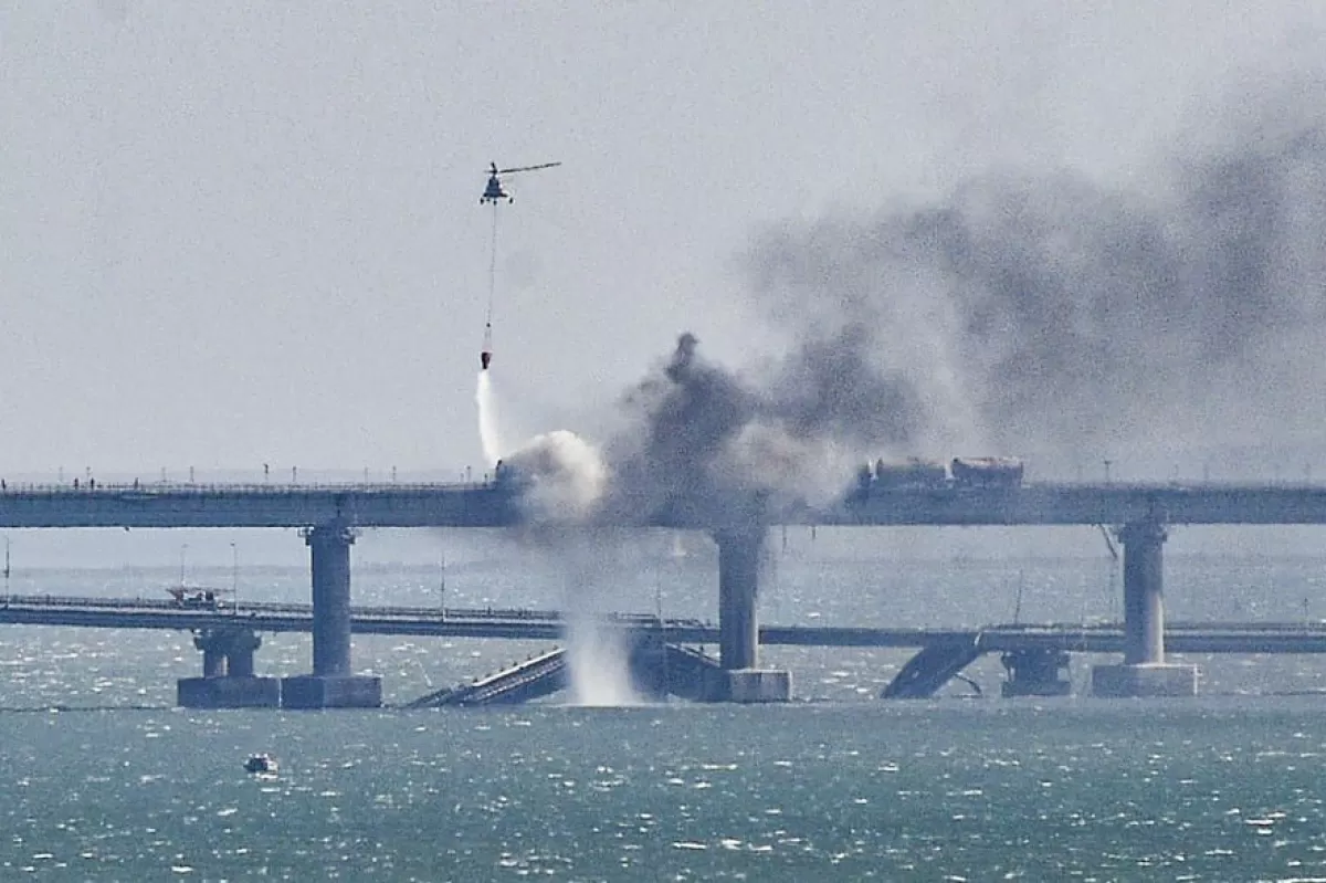Un elicopter de pompieri aruncă apă în focul de pe o parte prăbușită a podului peste strâmtoarea Kerci din Crimeea, 8 octombrie 2022.