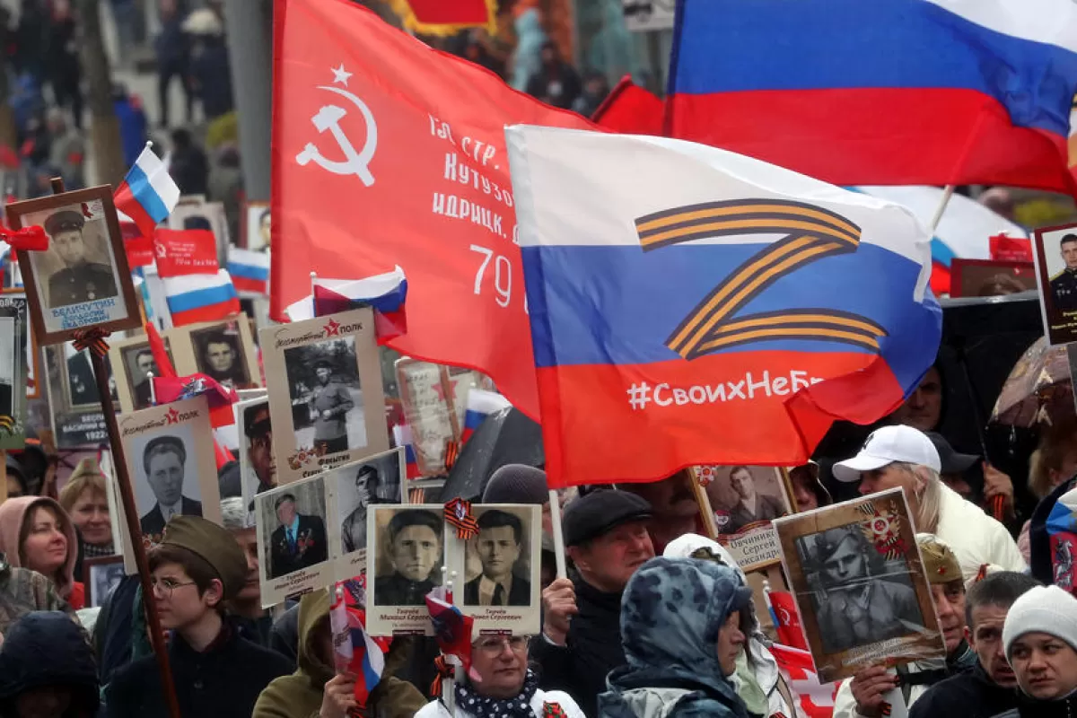 O persoană poartă un steag cu litera Z lângă oameni care țin portrete ale rudelor lor care au luptat în cel de-al Doilea Război Mondial, în timpul unui memorial al Regimentului Nemuritor la Moscova, Rusia, 9 mai 2022.