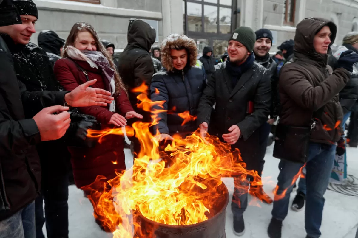 Activiștii ucraineni se încălzesc în timpul unui protest din 2018, în fața sediului Companiei de stat Naftogaz din Kiev, Ucraina, împotriva corupției în sectorul gazelor și a creșterii prețului pentru consumatori.