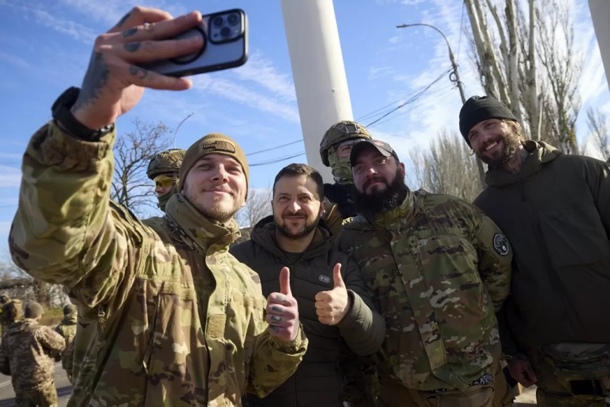 O fotografie pusă la dispoziție de serviciul de presă prezidențial ucrainean îl arată pe președintele Volodimir Zelenski pozând pentru un selfie cu militari în timp ce vizitează orașul recucerit Herson, Ucraina, 14 noiembrie 2022.