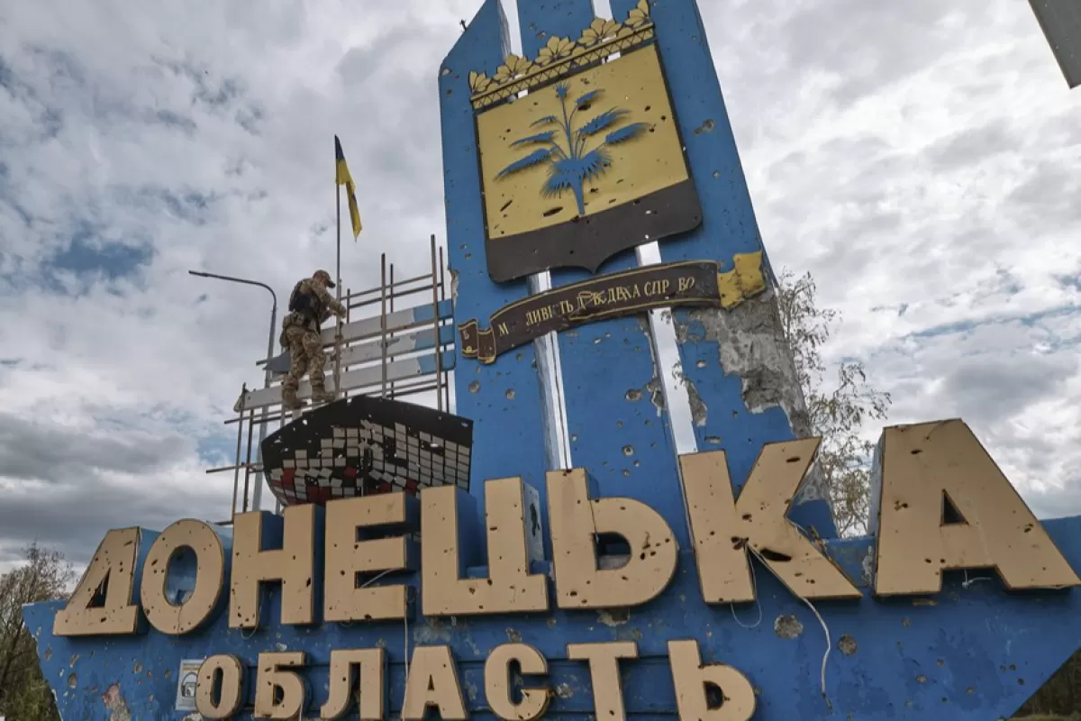 Un soldat ucrainean instalează un steag național pe stela cu „Oblast Donețk” la o graniță simbolică între zonele Harkov și Donețk, Ucraina, 20 septembrie 2022.