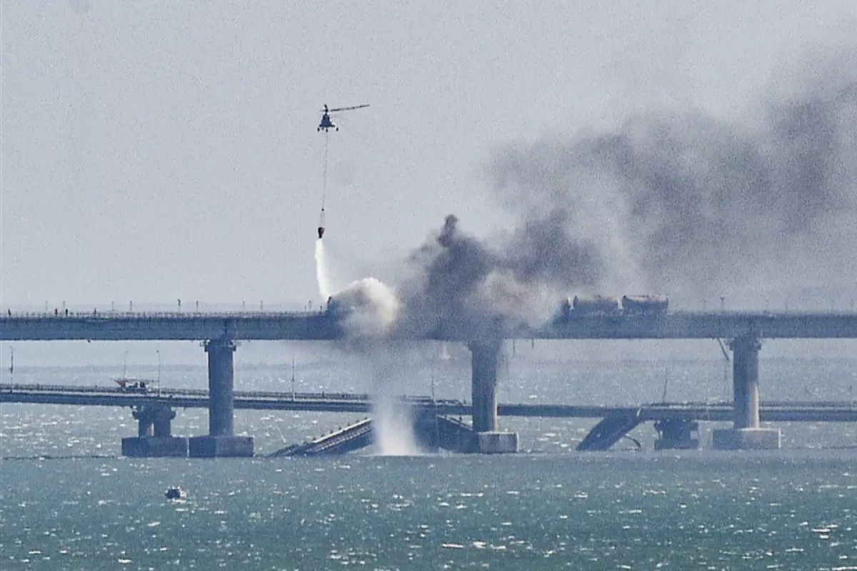 Un elicopter de pompieri aruncă apă în foc pe o parte prăbușită a podului strâmtoarea Kerci din Crimeea, 8 octombrie 2022.