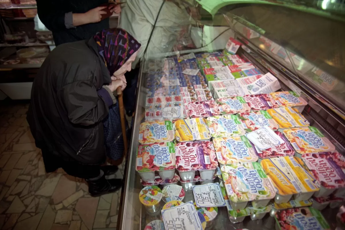 An elderly woman look at the window in the food store