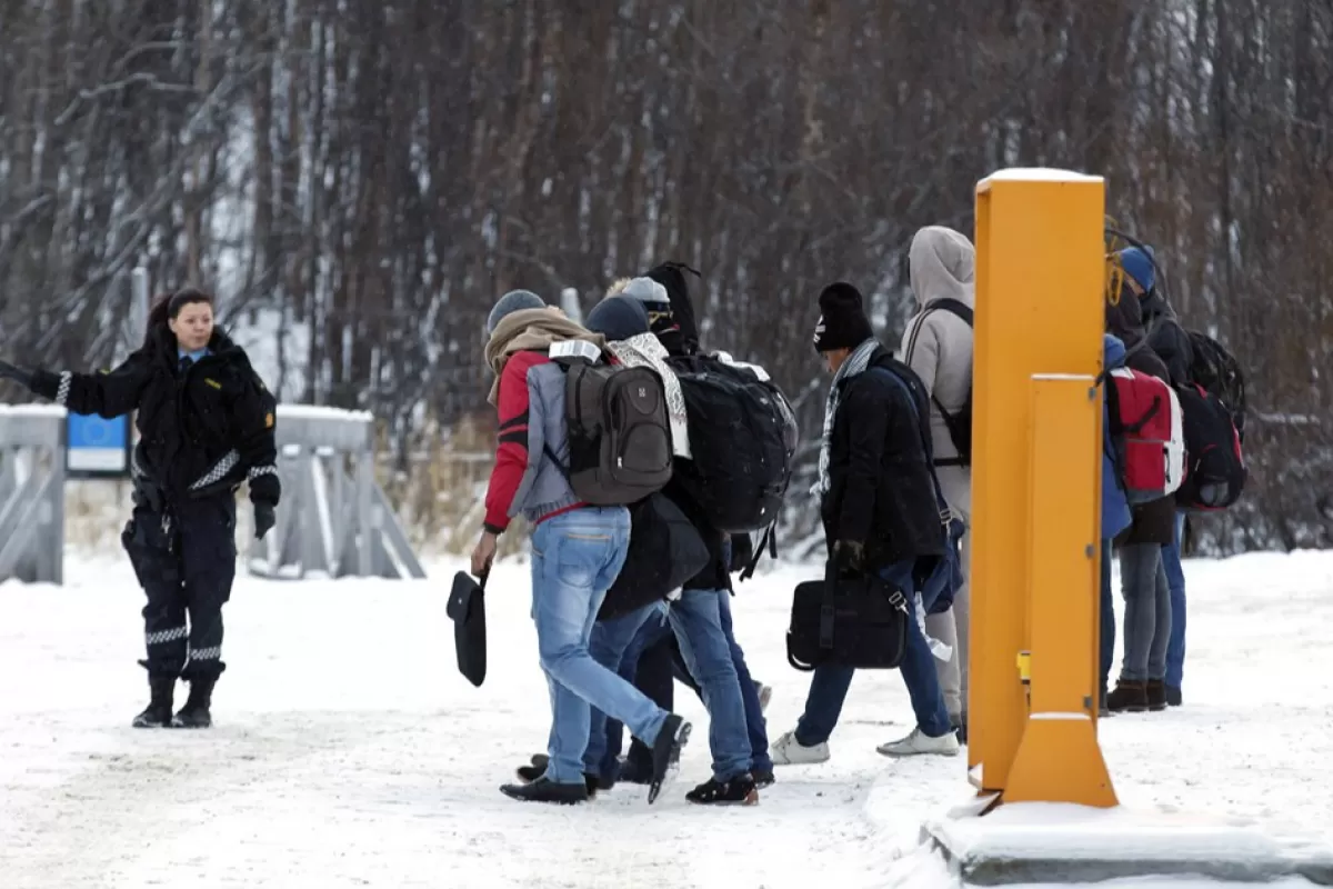 Refugiații primesc instrucțiuni de la un ofițer de poliție norvegian după ce au trecut granița dintre Norvegia și Rusia în Storskog, lângă Kirkenes, în nordul Norvegiei, 16 noiembrie 2015.