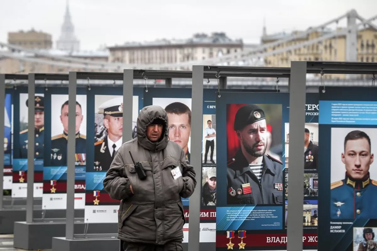 Un agent de pază trece pe lângă fotografii cu militari care au luptat în Ucraina în timpul unei expoziții stradale „Eroi cu o inimă eternă rusă” la Moscova, Rusia, 17 octombrie 2022.
