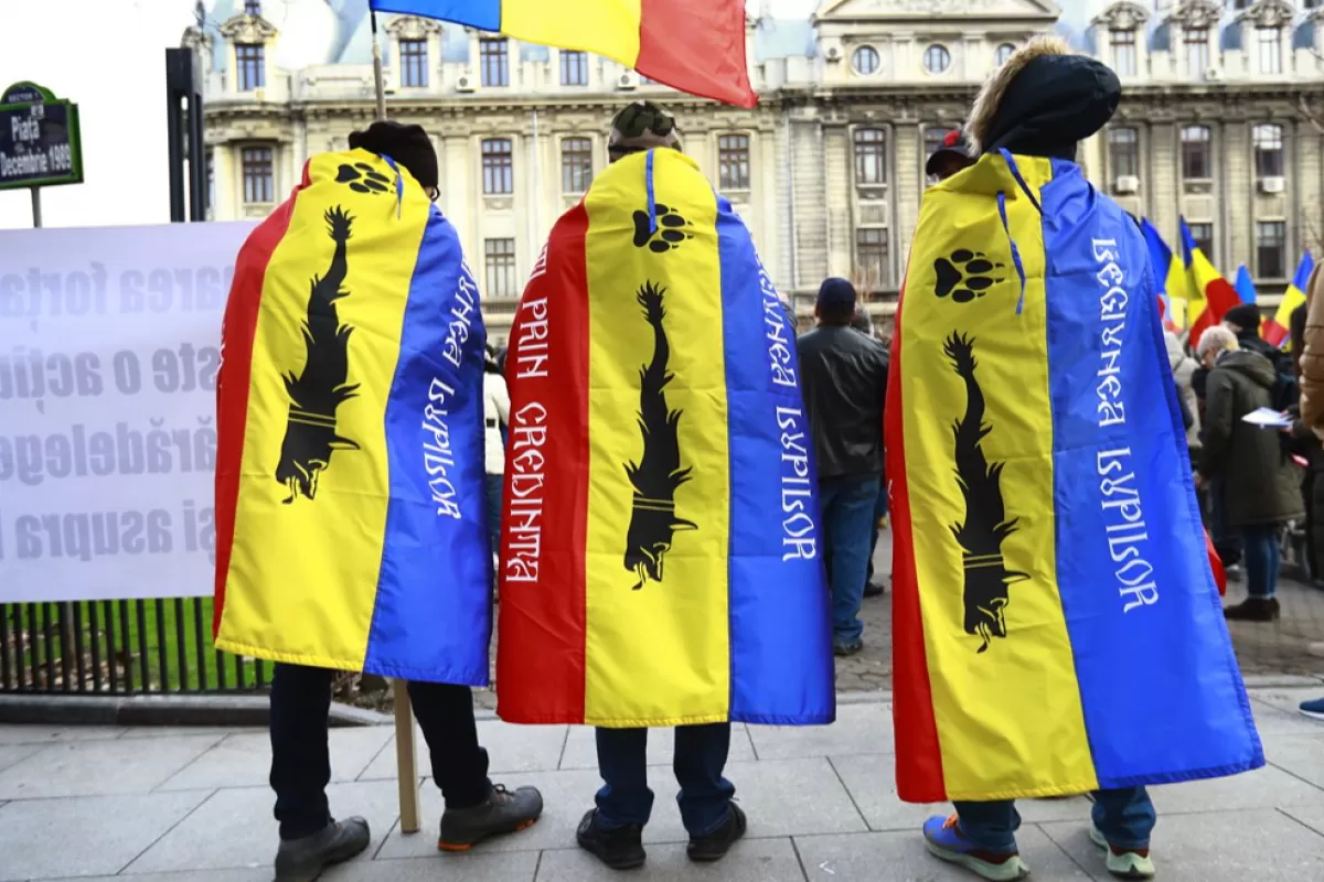 Three young Romanian nationalists men wear national flags labeled with black wolves on their shoulders, during a protest against a new mandatory vaccination law project and against new measures ordered by the Romanian government during the third wave of the Covid-19 Coronavirus pandemic, at University Plaza in Bucharest, Romania, 20 March 2021.