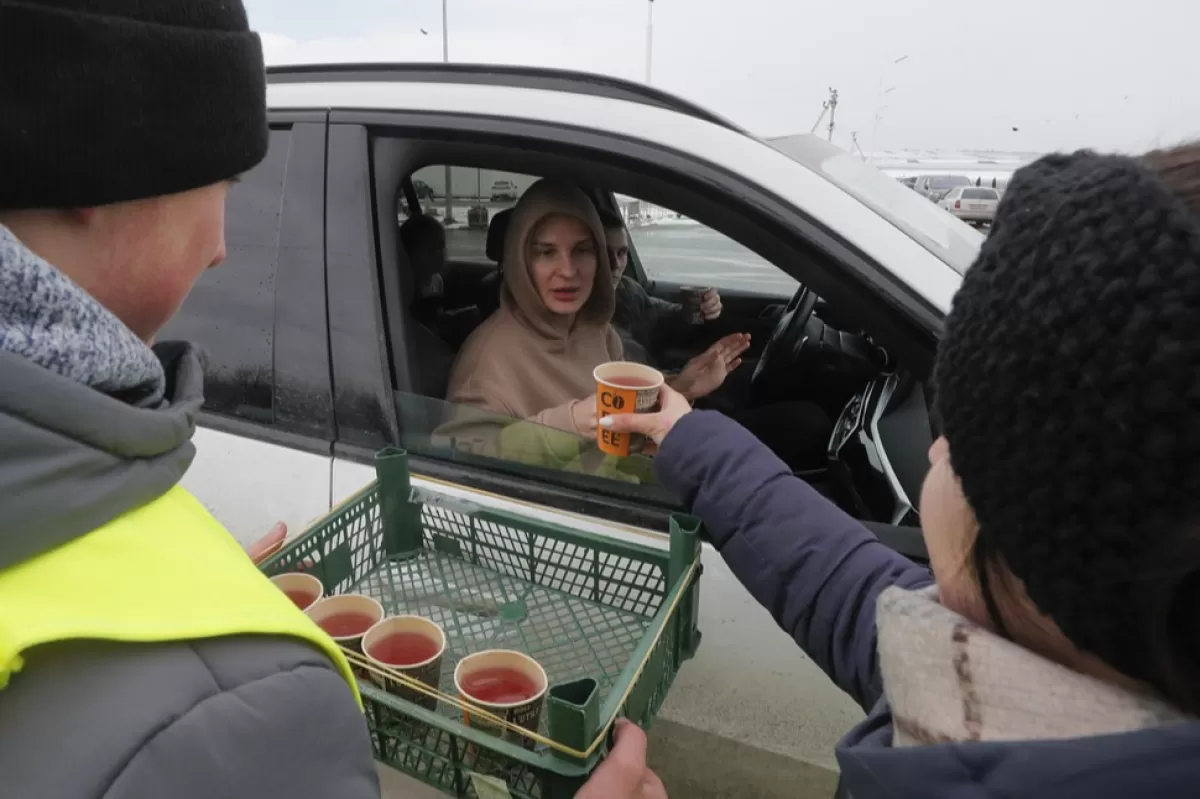 Voluntarii distribuie mâncare și ceai cald pentru persoanele care așteaptă la punctul de trecere a frontierei Ucraina - România, nu departe de orașul Cernăuți, Ucraina, 10 martie 2022.