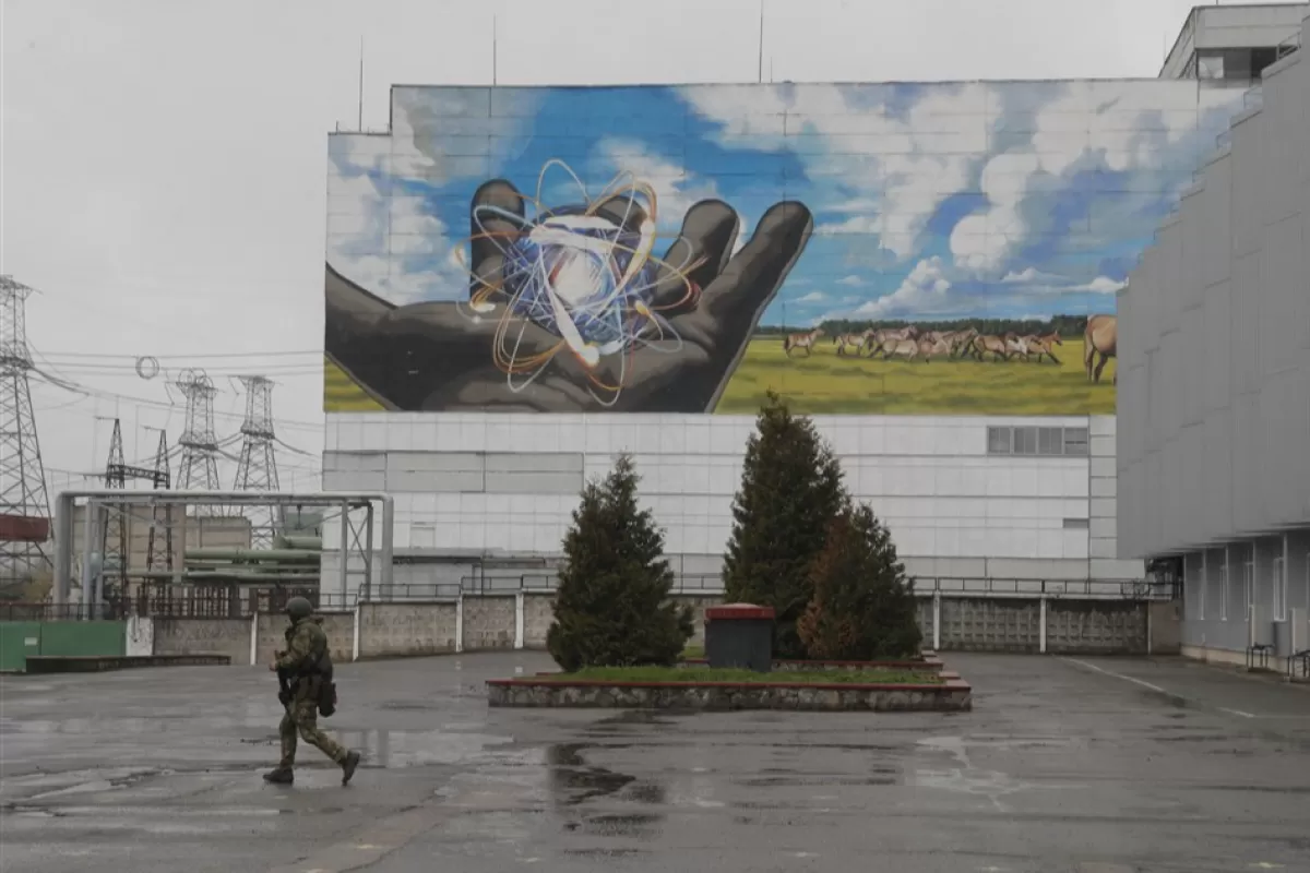 | Боец вооруженной национальной гвардии идет перед зданием Чернобыльской атомной электростанции, Украина, 26 апреля 2022 года