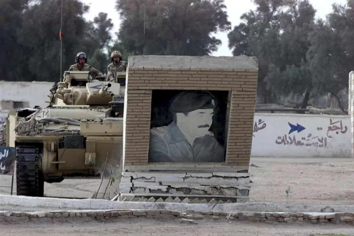 Members of the Desert Rats, British Royal Fusiliers, drive their Warrior tank into a picture of Iraqi leader Saddam Hussein in Basra, Southern Iraq, Monday 24 March 2003.