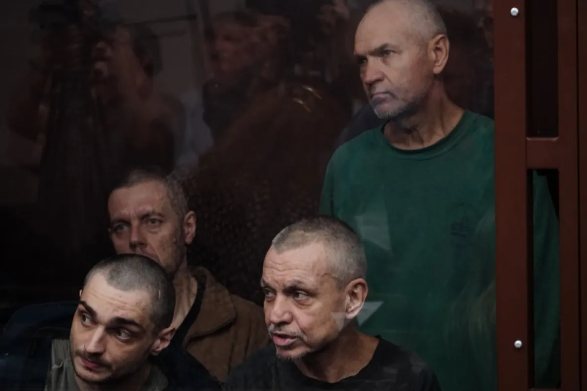 Prizonierii de război ucraineni stau în cușca acuzaților în timpul unei audieri la Tribunalul Militar din Districtul Sud din Rostov-pe-Don, Rusia, 14 iunie 2023. Douăzeci și patru de prizonieri ucraineni din batalionul „Azov”, capturați la Mariupol, sunt acuzați de participarea la o organizație teroristă și de alte crime. Aceștia riscă 15 ani într-o colonie cu regim strict până la închisoare pe viață.