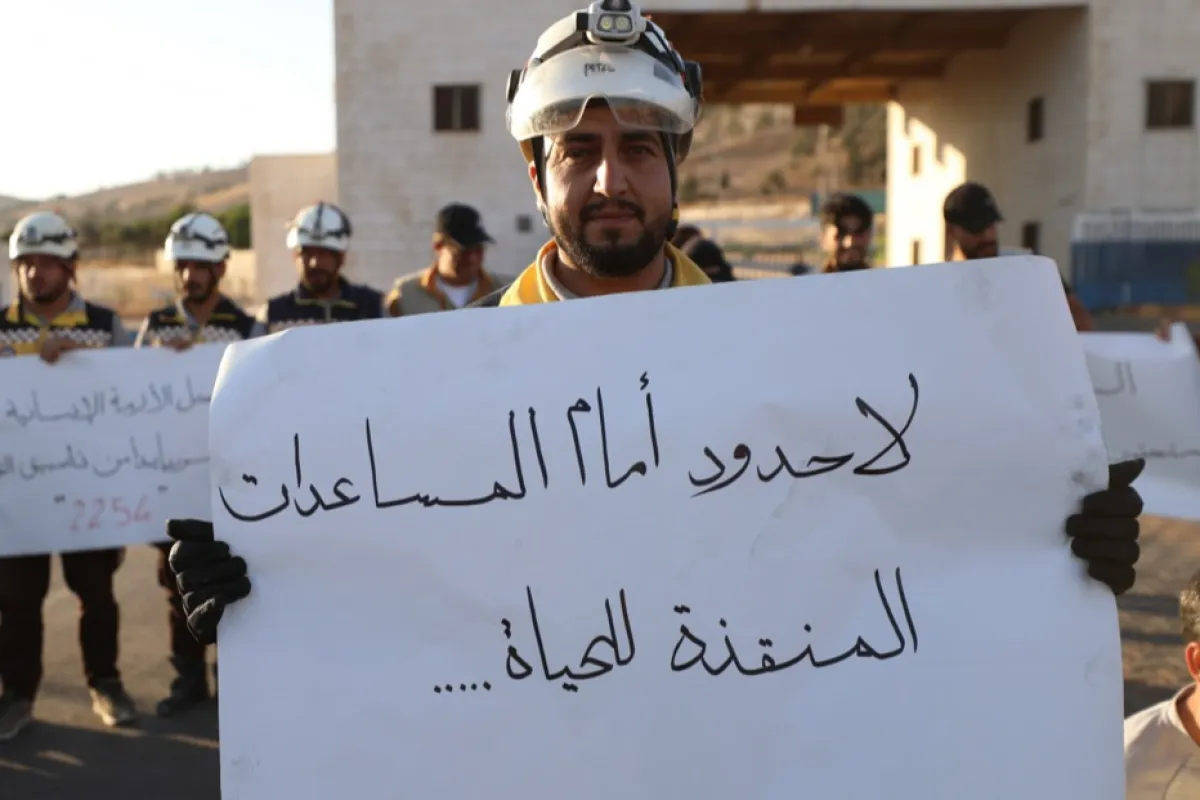 Un bărbat ține o pancartă pe care scrie în arabă „fără frontieră în fața ajutorului care salvează vieți”, în timpul unui protest după ce Rusia a respins prelungirea mandatului Consiliului de Securitate al ONU privind operațiunile de ajutor transfrontalier, la punctul de trecere a frontierei Bab Al-Hawa, Siria, 17 ani iulie 2023.