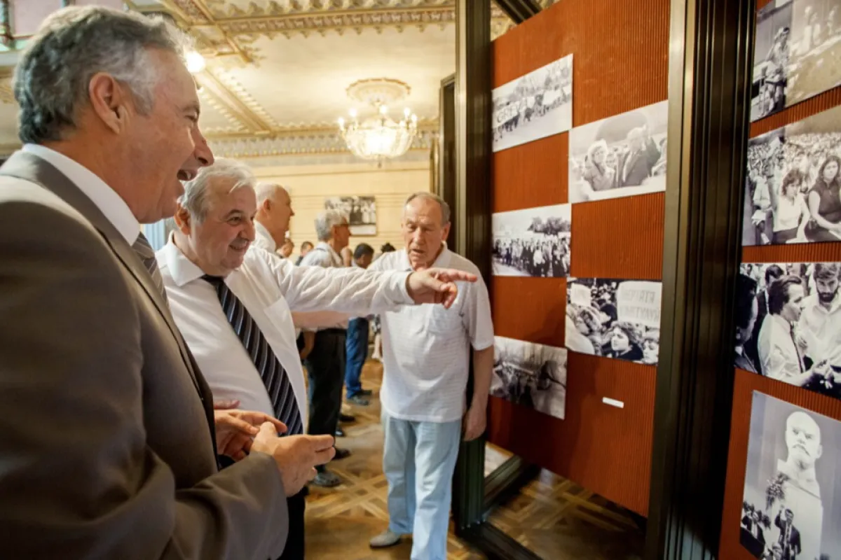 Former deputy of the first Moldova's Parliament Valeriu Matei (2L) next to former defense minister and general Victor Gaiciuc (L) points to a picture in which he found himself at the photography exhibition by photojournalist Tudor Iovu, dedicated to events marked the movement to Moldova's independence, at the National Museum of Ethnography and Natural History in Chisinau, Moldova, 26 August 2016.
