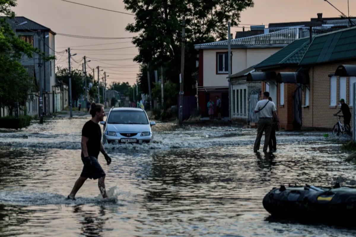 People walk in a flooded street of Kherson, Ukraine, 06 June 2023.Ukraine has accused Russian forces of destroying a critical dam and hydroelectric power plant on the Dnipro River in the Kherson region along the front line in southern Ukraine on 06 June.