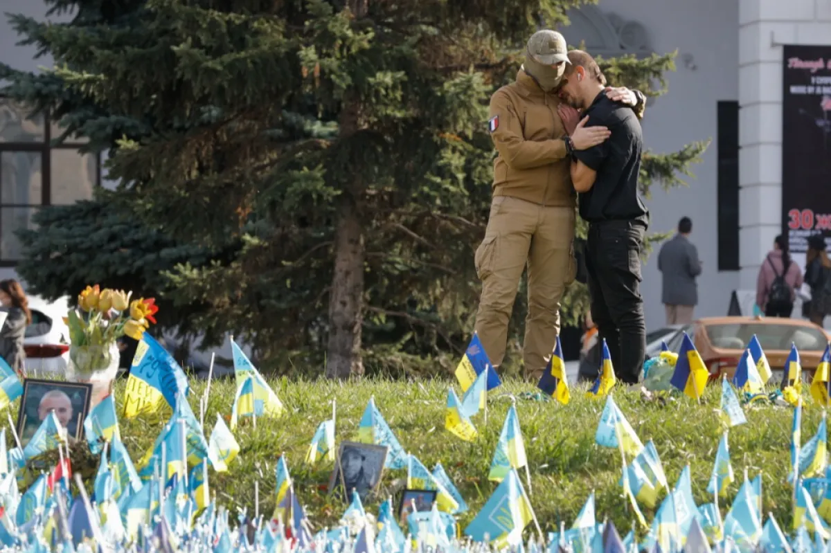 Doi bărbați se îmbrățișează lângă steagurile așezate în Piața Independenței în memoria militarilor ucraineni căzuți, în centrul orașului Kiev, Ucraina, 30 octombrie 2023.