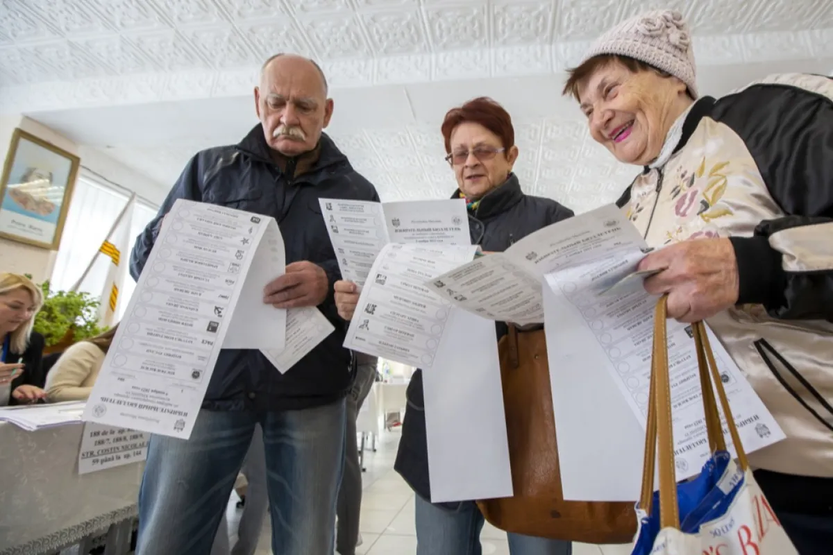 Oamenii se uită la buletinele de vot la o secție de votare în timpul alegerilor locale din Chișinău, Moldova, 05 noiembrie 2023.
