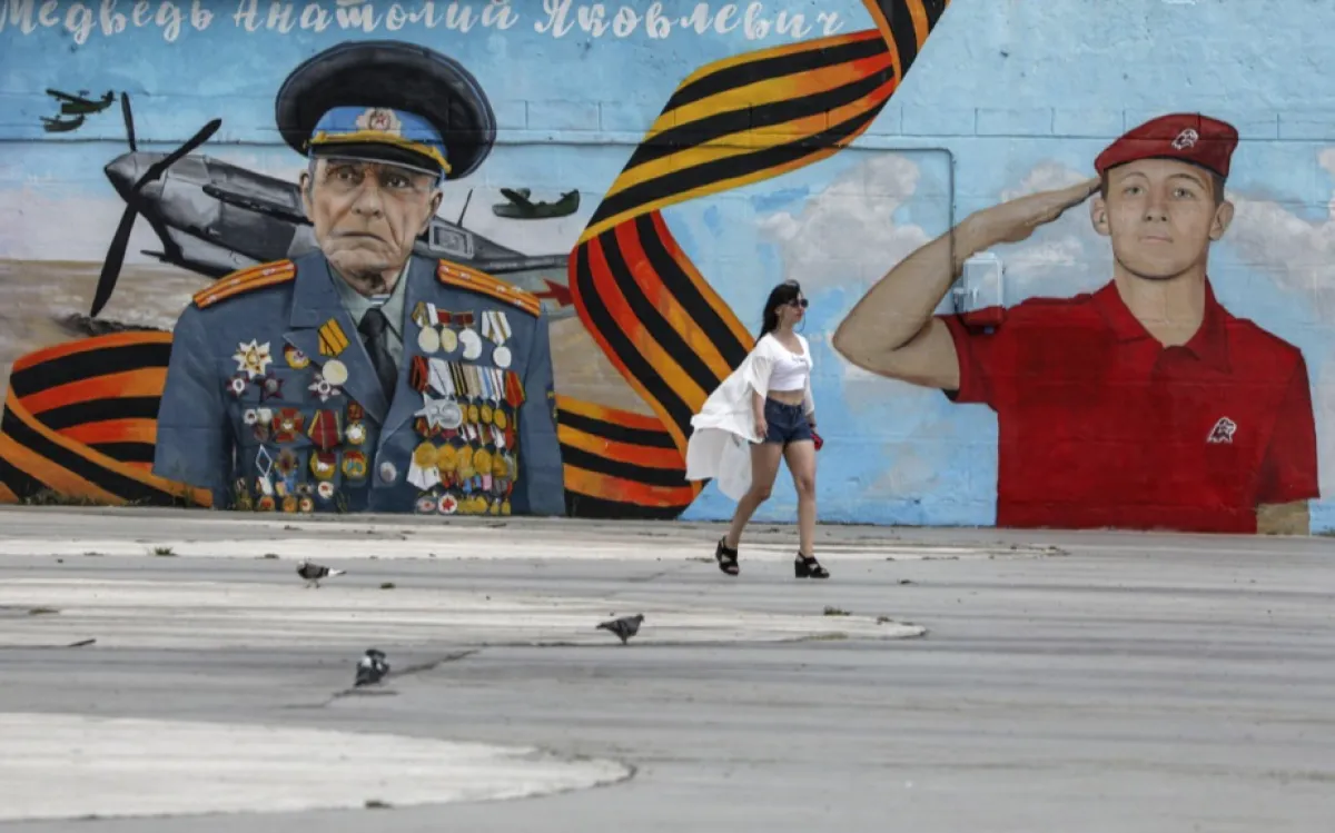 O femeie trece pe lângă o pictură murală patriotică în stațiunea de la Marea Neagră Yalta, Crimeea, 24 iulie 2023
