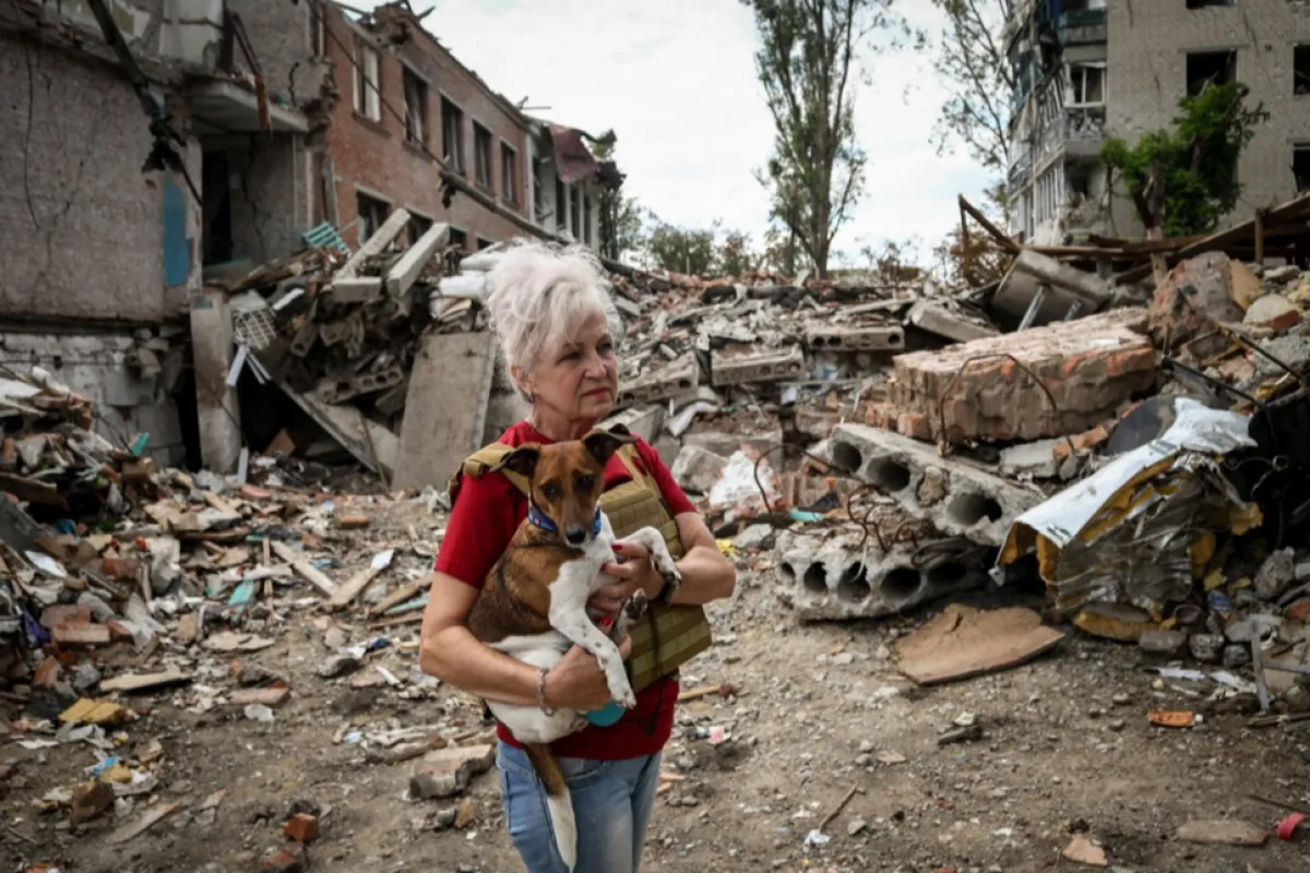 Lubov Jarova își ține în brațe câinele, Peremoha (victorie), în timp ce se plimbă printre dărâmăturile unei școli din orașul din prima linie Orikhiv, regiunea Zaporizhzhia, Ucraina, 7 septembrie 2023, pe fondul invaziei ruse.
