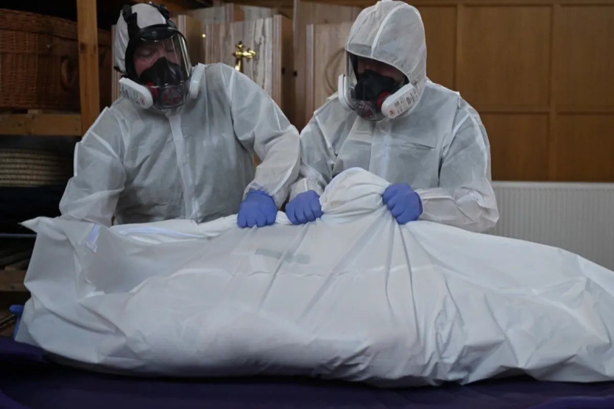 Mortuary workers wear protective suits as they move the body of a person who died from coronavirus at the mortuary of Poppy's Funerals in London, Britain, 24 April 2020.