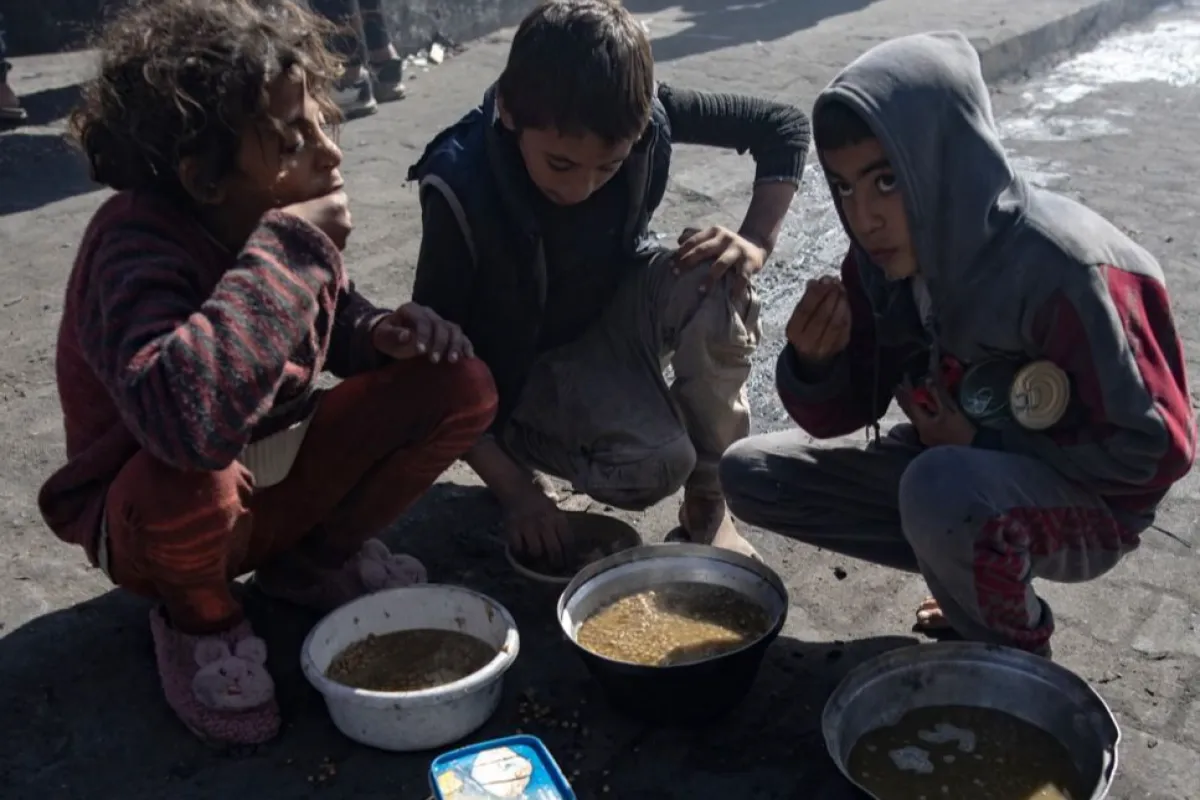 Displaced Palestinians queue to receive food at Rafah camp