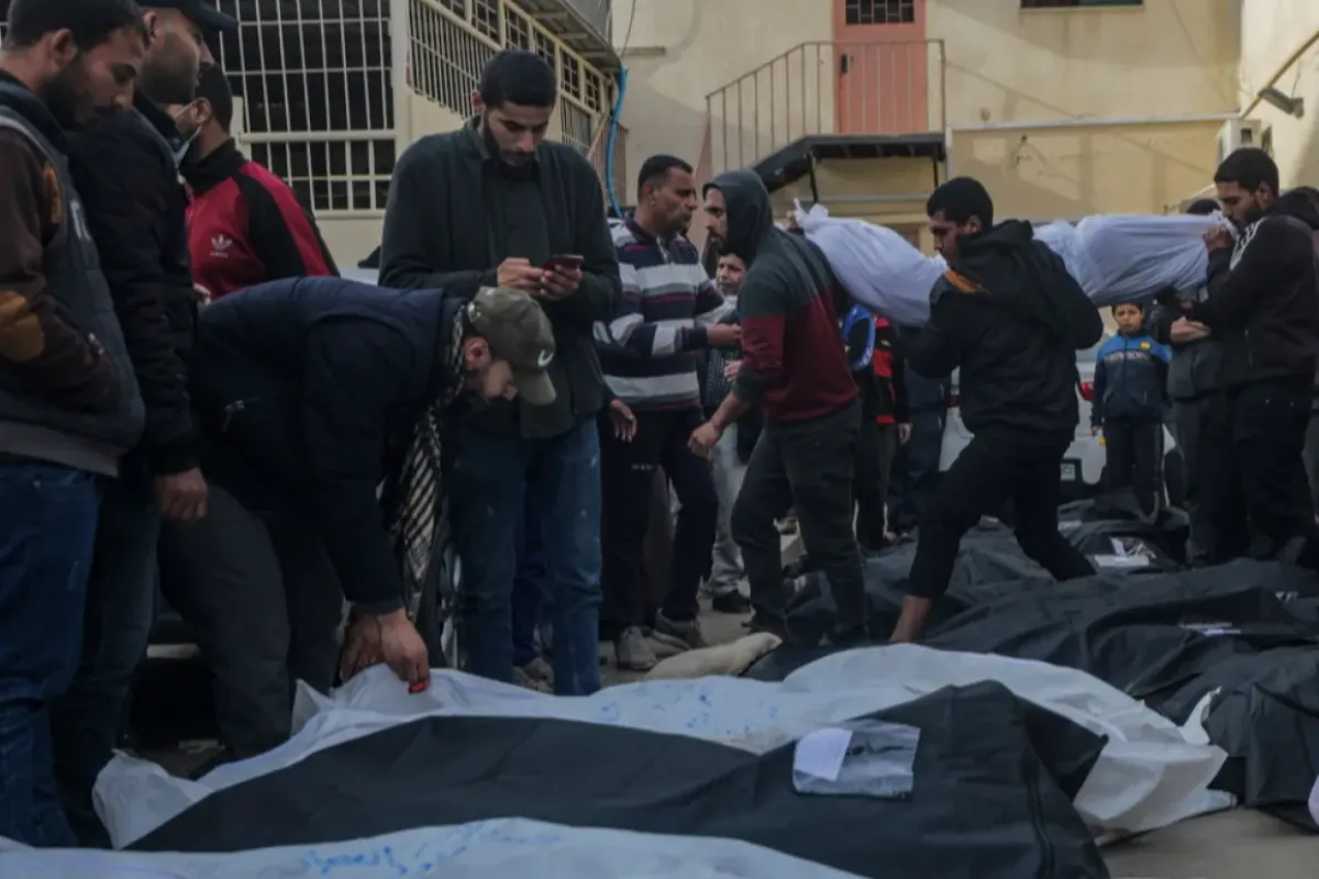 Palestinienii plâng lângă corpurile acoperite ale victimelor în urma unui atac aerian israelian asupra Deir Al Balah, în sudul Fâșiei Gaza, 23 februarie 2024.