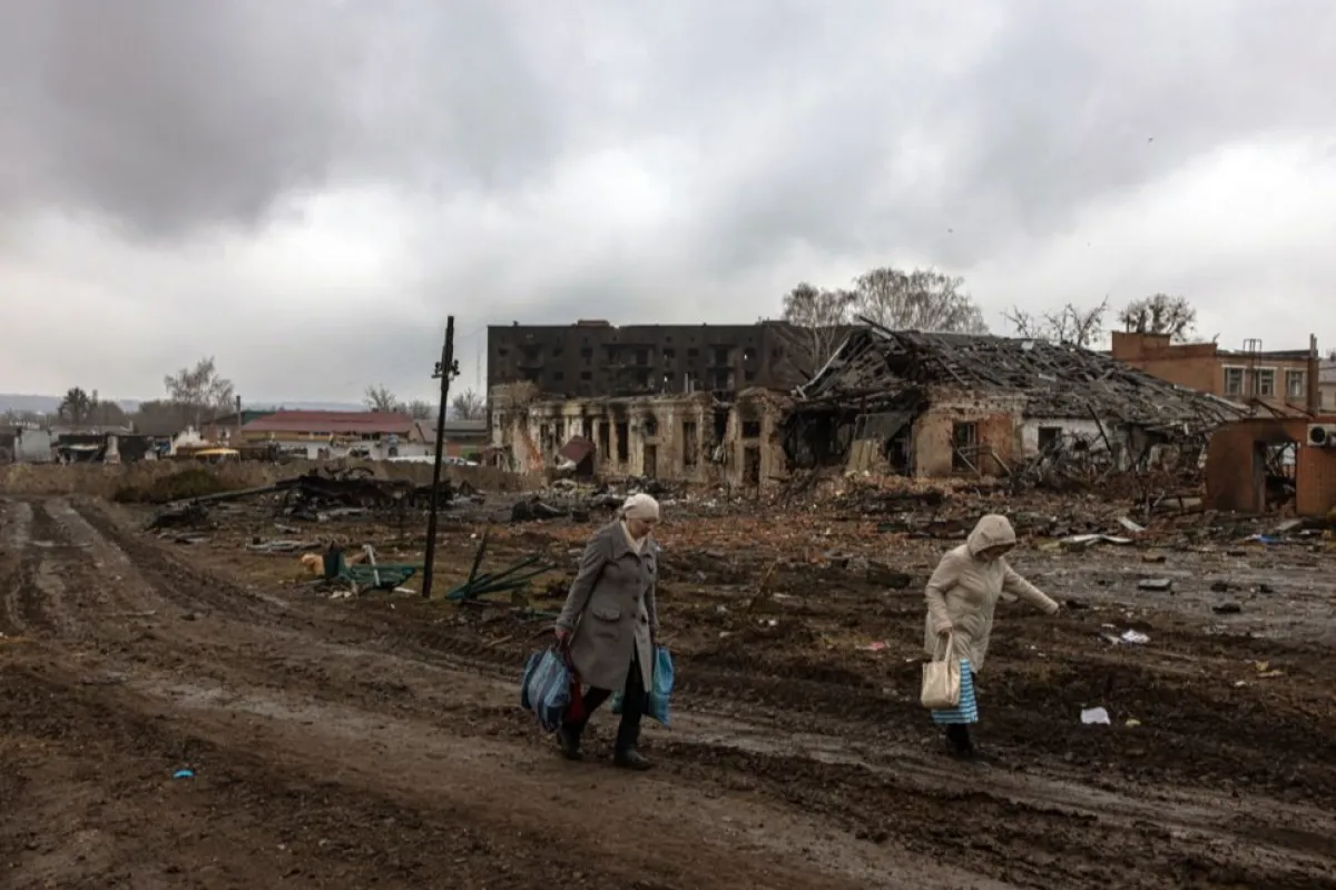 Locuitorii trec pe lângă clădirile distruse și vehiculele militare rusești, lângă gara unde erau staționate forțele ruse, în orașul Trostyanets, recucerit de armata ucraineană, în regiunea Sumi, Ucraina, 30 martie 2022.